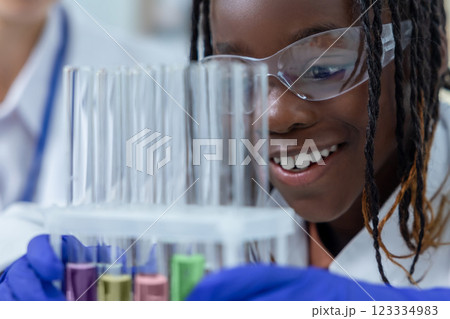 African American researcher with colleague working with tubes with colorful liquids African American researcher with colleague working with tubes with colorful liquids 123334983