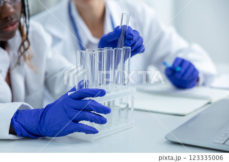 Unrecognizable medical women in lab holding pipettes conducting test on virus samples Unrecognizable medical women in lab holding pipettes conducting test on virus samples 123335006