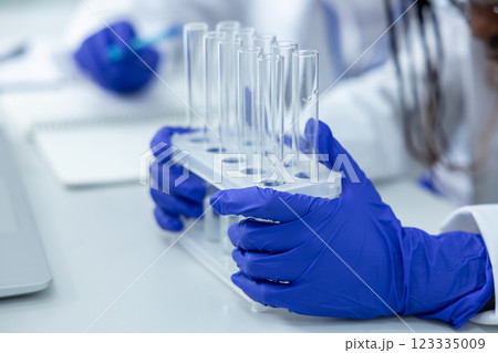 Unrecognizable medical woman in lab holding pipettes conducting test on virus samples 123335009