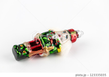 close up on white background, a lay glass enameled Christmas tree toy, handmade, a tin soldier nutcracker with decorative inserts and sparkles 123335035