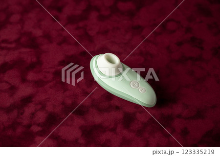 on red velvet background lies an open mint-colored vacuum vibrator mode buttons female pleasure toys for adults partner replacement relaxation and pleasure 123335219