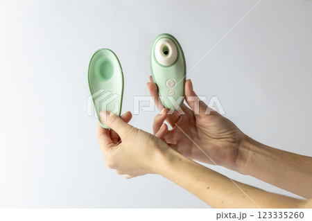 on white background female hands vacuum vibrator and its cover gently mint color device for girls relaxation for adults egg shape magnetic charging water resistance 123335260