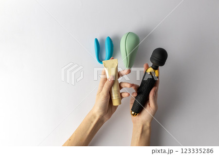 on white background, a woman s hand holds a large black vibrator in the shape of a microphone, lubricant in a tube, a vacuum mint and double blue vibrators lie nearby, various sex toys on white background, a woman s hand holds a large black vibrator in the shape of a microphone, lubricant in a tube, a vacuum mint and double blue vibrators lie nearby, various sex toys 123335286