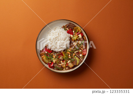 top shot on blue background black salad plate with Chinese rice and veal with vegetables sprinkled with nuts Asian cuisine healthy eating 123335331