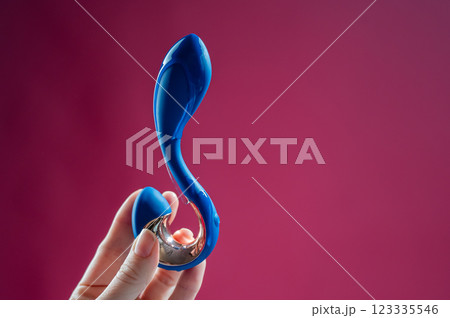 Lube pouring onto blue sex toy on pink background. Lube pouring onto blue sex toy on pink background. 123335546
