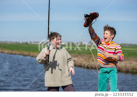 Funny fishing. Two of the boy's friends hooked an old shoe with a fishing rod and are laughing. 123335552