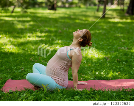 Pregnant caucasian woman doing yoga in the park.  123335623