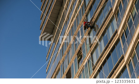 A man washes the windows of a skyscraper. Industrial alpinism. 123335631