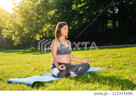 Woman sitting on the mat in park and meditating Woman sitting on the mat in park and meditating 123335686