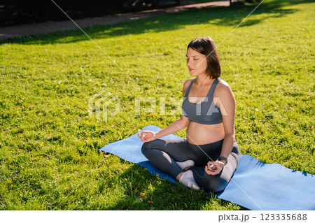 Woman sitting on the mat in park and meditating 123335688