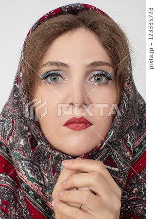 A woman with a scarf on her head and red lips. She has a serious look on her face 123335728