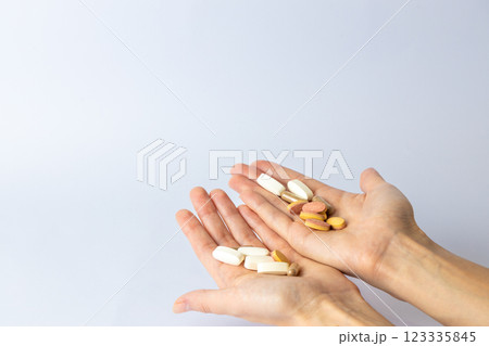 on white background, on the outstretched palms of female hands, there are pills and vitamins of different shapes and colors. suicidal thoughts, depression, health care. 123335845