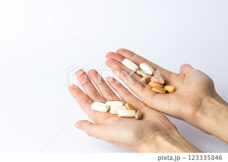 on white background, on the outstretched palms of female hands, there are pills and vitamins of different shapes and colors. suicidal thoughts, depression, health care. 123335846