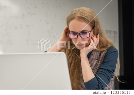 Caucasian woman scientist typing on laptop. White board with formulas. Caucasian woman scientist typing on laptop. White board with formulas. 123336113