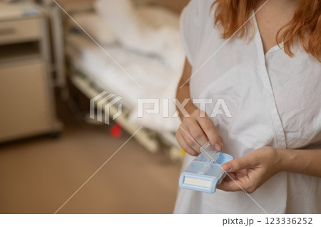 Close up of hands. Woman holding pillbox in hospital.  123336252