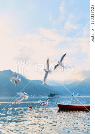Flock of seagulls flies low over the sea against the background of mountains 123337528