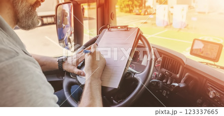 Truck driver sitting in the car and writing documents. 123337665