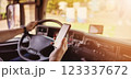Truck driver sitting behind the wheel and looking at the smartphone. 123337672
