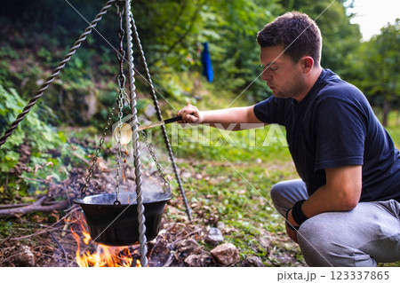 Hiker preparing food on campfire in forest 123337865