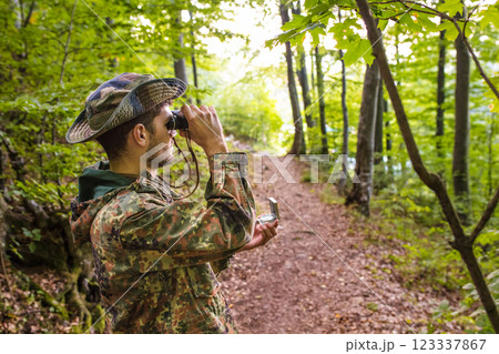 Soldier using binoculars and compass in forest Soldier using binoculars and compass in forest 123337867