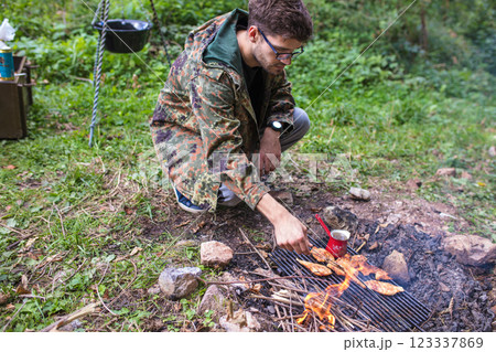 Man grilling chicken on a campfire in the forest 123337869