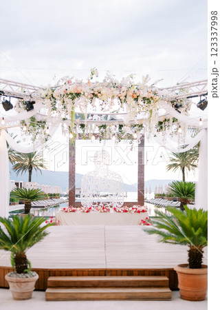 Stage with a round canopy decorated with flowers near a wicker sculpture near a square frame in a swimming pool 123337998