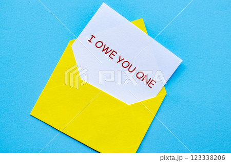 Yellow envelope on a blue cover with a white card partially pulled out with I Owe You One text 123338206