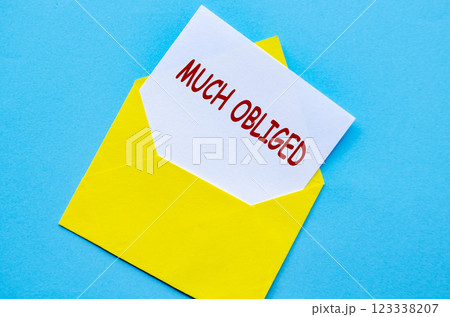Yellow envelope on a blue cover with a white card partially pulled out with Much Obliged text Yellow envelope on a blue cover with a white card partially pulled out with Much Obliged text 123338207