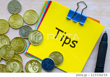 Tips text on yellow paper covered with white envelope and surrounded by golden coins 123338219