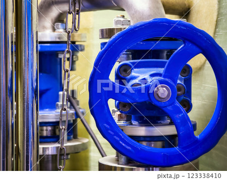 Industrial valve with blue handle and metal components in a factory setting 123338410