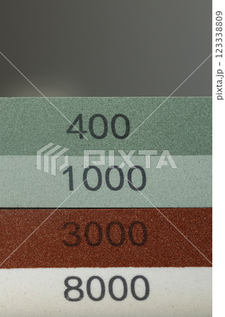 closeup dark background on table lies red and green equipment a set for sharpening and polishing kitchen knives and various blades different abrasiveness of stones a retainer for knives closeup dark background on table lies red and green equipment a set for sharpening and polishing kitchen knives and various blades different abrasiveness of stones a retainer for knives 123338809