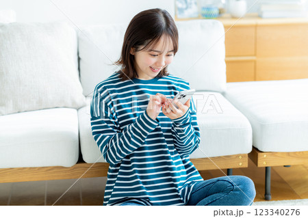 部屋でスマホを操作する若い女性 123340276