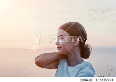 Girl Looking at Sunset with Hand on Shoulder 123340954