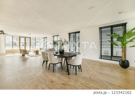 A spacious modern dining and living area with natural light, featuring elegant furniture and indoor plants that enhance the ambiance. A spacious modern dining and living area with natural light, featuring elegant furniture and indoor plants that enhance the ambiance. 123342162