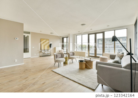 Bright and spacious modern living room featuring stylish furniture, large windows, and wooden flooring that creates a welcoming atmosphere. Bright and spacious modern living room featuring stylish furniture, large windows, and wooden flooring that creates a welcoming atmosphere. 123342164