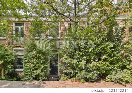 This image showcases a charming brick house enveloped in vibrant greenery, exemplifying a harmonious blend of architecture and nature. 123342214