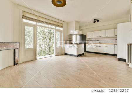 An elegantly designed kitchen featuring white cabinets, wooden flooring, and large windows that invite natural light, creating a bright and airy atmosphere. 123342297