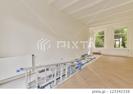 A light-filled room undergoing renovation with elegant wooden flooring and large windows, creating a welcoming atmosphere perfect for design. A light-filled room undergoing renovation with elegant wooden flooring and large windows, creating a welcoming atmosphere perfect for design. 123342338