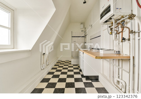 A spacious modern kitchen featuring a sleek design, a checkered floor pattern, and ample natural light from the windows. Ideal for contemporary home aesthetics. 123342376