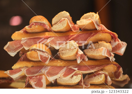 This image shows a stack of sandwiches. Each sandwich looks to be made with a small baguette or a similar type of bread, cut in half, and filled with slices of ham. The arrangement of sandwiches is This image shows a stack of sandwiches. Each sandwich looks to be made with a small baguette or a similar type of bread, cut in half, and filled with slices of ham. The arrangement of sandwiches is 123343322