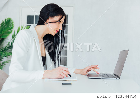 Brunette Woman In White Business Suit With Laptop Online In Office At Training Brunette Woman In White Business Suit With Laptop Online In Office At Training 123344714
