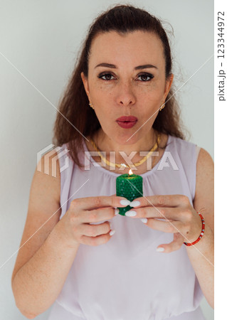Beautiful brunette woman blowing out a green candle Beautiful brunette woman blowing out a green candle 123344972