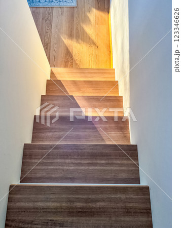 Sunlit wooden staircase descends into a hallway, casting sharp shadows . High quality photo Sunlit wooden staircase descends into a hallway, casting sharp shadows . High quality photo 123346626