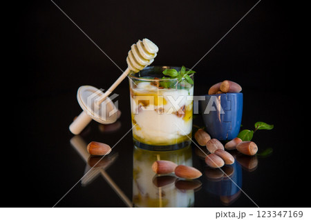 homemade yogurt with kiwi, honey and nuts in a glass, isolated on black background homemade yogurt with kiwi, honey and nuts in a glass, isolated on black background 123347169