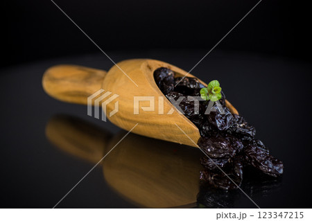 Prunes in a wooden spoon on a dark background 123347215