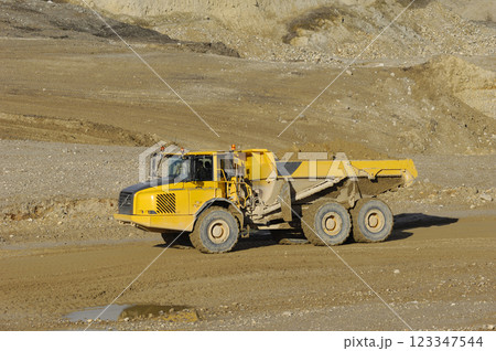 Yellow dump truck working in gravel pit 123347544
