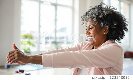Happy elderly lady enjoying exercise in fitness room in bright morning sun in gym, copy space for health and exercise concept for seniors 123348053