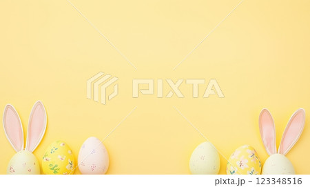 Colorful Easter eggs and bunny ears create festive atmosphere on pastel yellow background 123348516