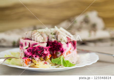 layered vegetable salad with beets and herring, on a wooden table layered vegetable salad with beets and herring, on a wooden table 123348814