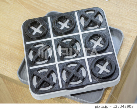 Model of the toy Tic-tac-toe printed on 3D printer close-up. Object created on 3D printer from molten plastic of black and white color. 3D printing technology. Additive modern progressive technologies Model of the toy Tic-tac-toe printed on 3D printer close-up. Object created on 3D printer from molten plastic of black and white color. 3D printing technology. Additive modern progressive technologies 123348908